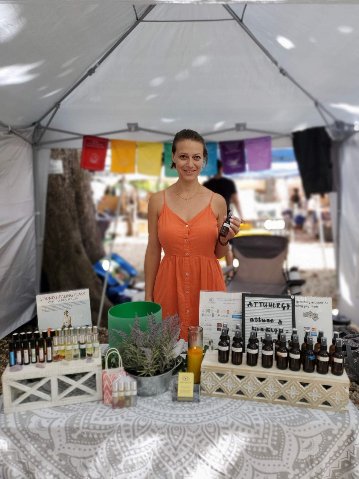 Jessica of Attunergy standing behind table full of aromatherapy products at fair.